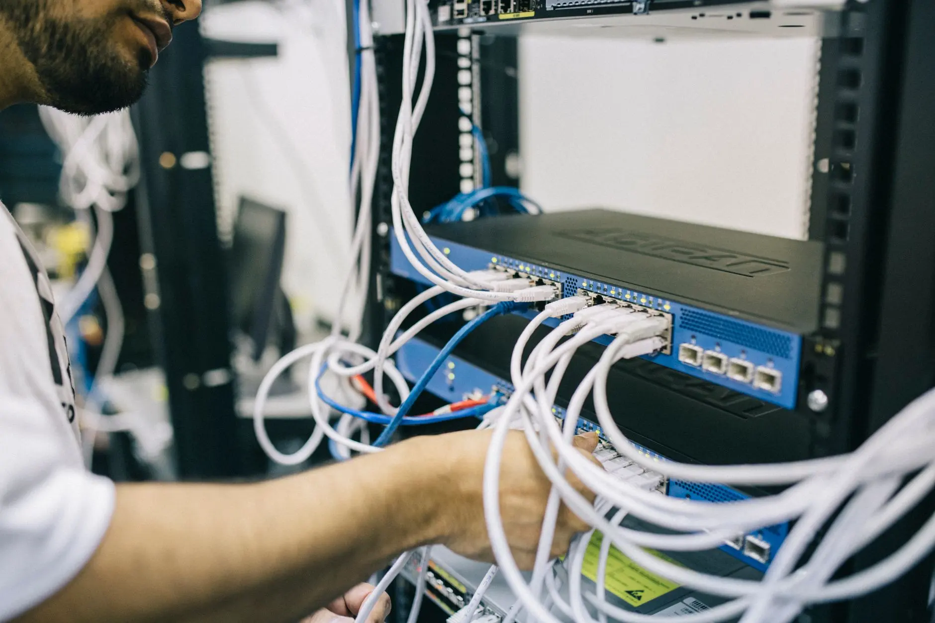 Person som kopplar nätverkskablar i ett serverrack